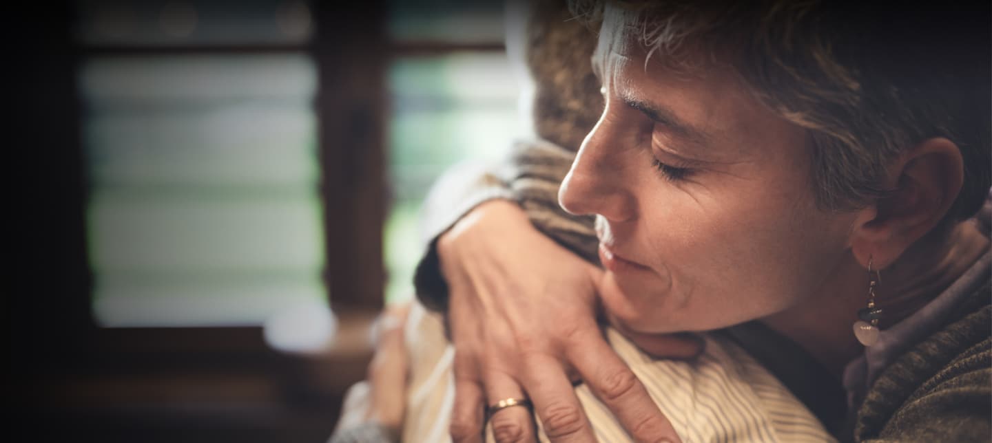 Close-up of a woman with eyes closed, gently hugging someone in a comforting embrace