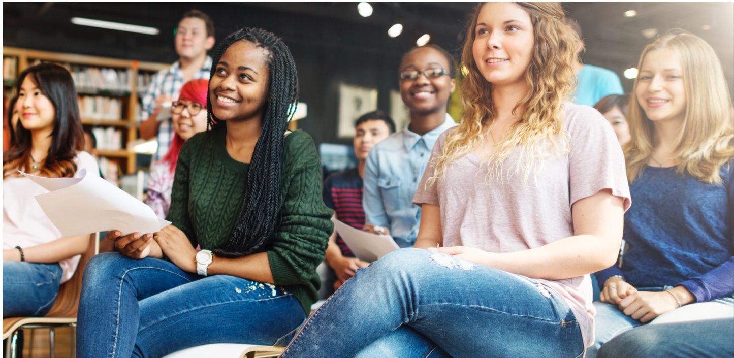 Diverse group of students sitting together in classroom with papers