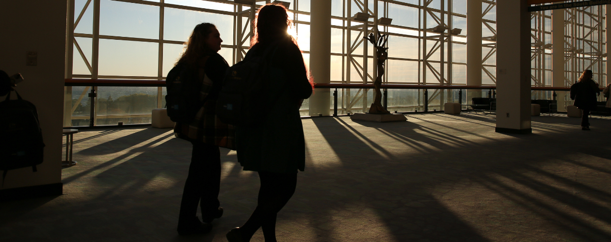Conference attendees walking past large windows.